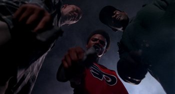 Movie still from “Tales from the Hood” (1995), directed by Rusty Cundieff – A group of men standing around each other; Medium shot, Low angle