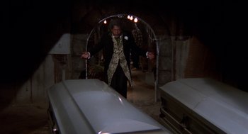 Movie still from “Tales from the Hood” (1995), directed by Rusty Cundieff – A man standing in front of a coffin in a tunnel; Wide shot, High angle
