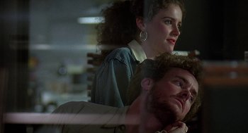 Movie still from “Talk Radio” (1988), directed by Oliver Stone – A man and a woman standing next to each other in a room; Close Up shot, Low angle