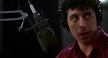 Movie still from “Talk Radio” (1988), directed by Oliver Stone – A man wearing headphones and standing in front of a microphone; Close Up shot, Low angle