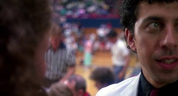 Movie still from “Talk Radio” (1988), directed by Oliver Stone – A group of people standing around in a room; Close Up shot, Over the shoulder angle