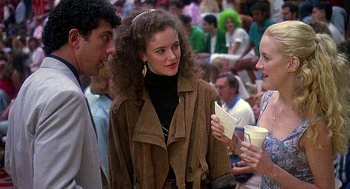 Movie still from “Talk Radio” (1988), directed by Oliver Stone – A group of people standing in a crowd talking to each other; Medium shot, Over the shoulder angle