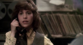 Movie still from “Talk Radio” (1988), directed by Oliver Stone – A woman in a yellow shirt and black vest; Close Up shot, High angle