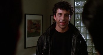 Movie still from “Talk Radio” (1988), directed by Oliver Stone – A man in a leather jacket smiling for the camera; Close Up shot, Low angle