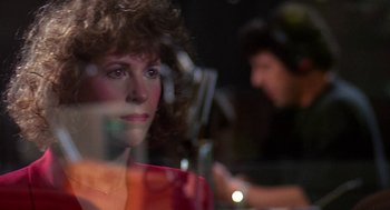 Movie still from “Talk Radio” (1988), directed by Oliver Stone – A person behind a glass window; Close Up shot, Over the shoulder angle