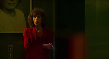 Movie still from “Talk Radio” (1988), directed by Oliver Stone – A woman in a red jacket smoking a cigarette; Medium shot, Over the shoulder angle