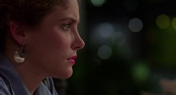 Movie still from “Talk Radio” (1988), directed by Oliver Stone – A person's face with a blurry background; Close Up shot, Over the shoulder angle