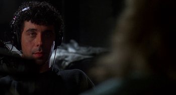 Movie still from “Talk Radio” (1988), directed by Oliver Stone – A man with headphones is sitting in a dark room; Close Up shot, Over the shoulder angle