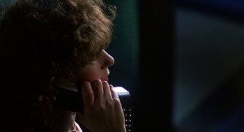 Movie still from “Talk Radio” (1988), directed by Oliver Stone – A woman is talking on a phone in the dark; Close Up shot, Low angle