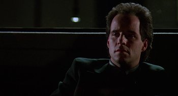 Movie still from “Talk Radio” (1988), directed by Oliver Stone – A man sitting in a chair in a dark room; Close Up shot, Low angle