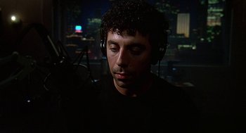 Movie still from “Talk Radio” (1988), directed by Oliver Stone – A man with headphones is listening to music in a recording studio; Close Up shot, Low angle
