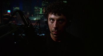 Movie still from “Talk Radio” (1988), directed by Oliver Stone – A man with headphones in a dark room; Close Up shot, Low angle
