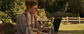 Movie still from “Tamara Drewe” (2010), directed by Stephen Frears – A woman sitting at a table using a computer; Medium shot, Over the shoulder angle