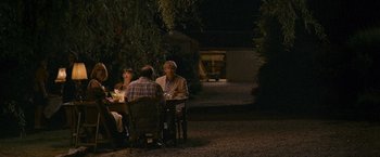 Movie still from “Tamara Drewe” (2010), directed by Stephen Frears – A group of people sitting around a table at night; Wide shot, Over the shoulder angle