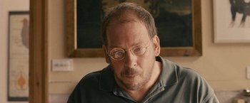 Movie still from “Tamara Drewe” (2010), directed by Stephen Frears – An older man wearing glasses and a gray shirt; Close Up shot, Over the shoulder angle