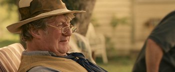 Movie still from “Tamara Drewe” (2010), directed by Stephen Frears – An older man wearing a hat and glasses; Close Up shot, Over the shoulder angle