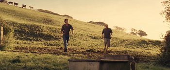 Movie still from “Tamara Drewe” (2010), directed by Stephen Frears – Two men are walking in a field near a wall; Wide shot, Low angle