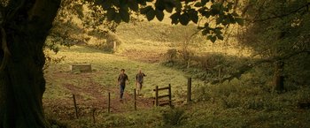 Movie still from “Tamara Drewe” (2010), directed by Stephen Frears – Two men are walking through a grassy field; Extreme Wide shot, High angle