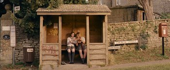 Movie still from “Tamara Drewe” (2010), directed by Stephen Frears – A couple of people sitting on top of a wooden bench; Wide shot, Low angle