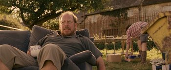 Movie still from “Tamara Drewe” (2010), directed by Stephen Frears – A person sitting in a chair outside; Medium shot, Over the shoulder angle