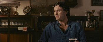 Movie still from “Tamara Drewe” (2010), directed by Stephen Frears – A person sitting in a room with a glass of wine; Medium shot, Over the shoulder angle