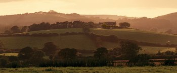 Movie still from “Tamara Drewe” (2010), directed by Stephen Frears – The sun is setting over a lush green field; Extreme Wide shot, Low angle