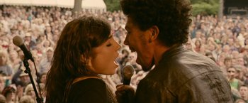 Movie still from “Tamara Drewe” (2010), directed by Stephen Frears – A man and a woman singing into microphones at an outdoor concert; Medium shot, High angle
