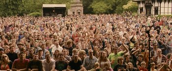 Movie still from “Tamara Drewe” (2010), directed by Stephen Frears – A large crowd of people sitting in a park; Extreme Wide shot, High angle