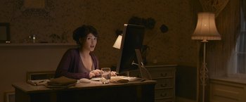 Movie still from “Tamara Drewe” (2010), directed by Stephen Frears – A woman sitting in front of a computer at a desk; Medium shot, Over the shoulder angle