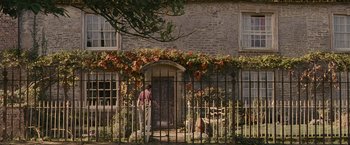 Movie still from “Tamara Drewe” (2010), directed by Stephen Frears – A man standing in front of a building with a gate; Extreme Wide shot, Low angle
