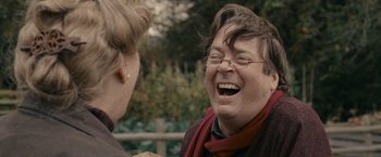 Movie still from “Tamara Drewe” (2010), directed by Stephen Frears – A woman with glasses is laughing with another woman; Close Up shot, Over the shoulder angle