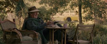 Movie still from “Tamara Drewe” (2010), directed by Stephen Frears – An older man sitting at a table outside; Medium shot, Over the shoulder angle