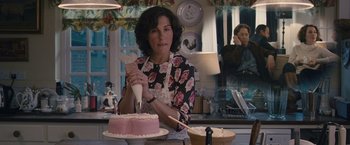 Movie still from “Tamara Drewe” (2010), directed by Stephen Frears – A woman in an apron is frosting a cake; Medium shot, Over the shoulder angle
