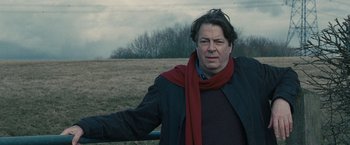 Movie still from “Tamara Drewe” (2010), directed by Stephen Frears – A man in a black jacket and a red scarf; Close Up shot, Over the shoulder angle