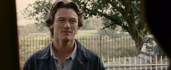 Movie still from “Tamara Drewe” (2010), directed by Stephen Frears – A person wearing a jacket near a fence; Close Up shot, Over the shoulder angle