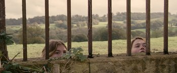 Movie still from “Tamara Drewe” (2010), directed by Stephen Frears – A young girl looking over a fence with a view of a field; Medium shot, Low angle