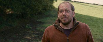 Movie still from “Tamara Drewe” (2010), directed by Stephen Frears – A person wearing glasses and a sweater; Close Up shot, Over the shoulder angle