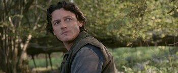 Movie still from “Tamara Drewe” (2010), directed by Stephen Frears – A person wearing a vest near a tree; Close Up shot, Over the shoulder angle