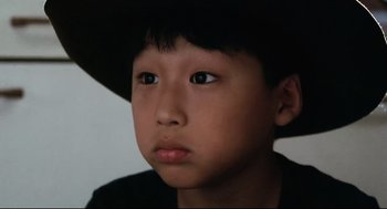 Movie still from “Tampopo” (1985), directed by Jûzô Itami – A young boy wearing a black hat looking at the camera; Close Up shot, High angle