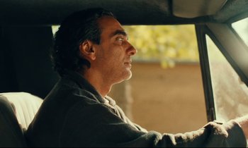 Movie still from “Taste of Cherry” (1997), directed by Abbas Kiarostami – A man sitting in the driver's seat of a car; Close Up shot, Over the shoulder angle
