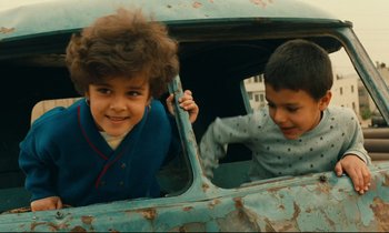 Movie still from “Taste of Cherry” (1997), directed by Abbas Kiarostami – Two children are looking out of a car window; Close Up shot, High angle