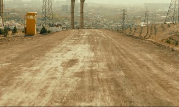 Movie still from “Taste of Cherry” (1997), directed by Abbas Kiarostami – A dirt road with power lines on the side of it; Extreme Wide shot, High angle