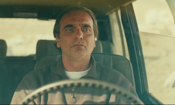 Movie still from “Taste of Cherry” (1997), directed by Abbas Kiarostami – A person driving a car; Close Up shot, Low angle