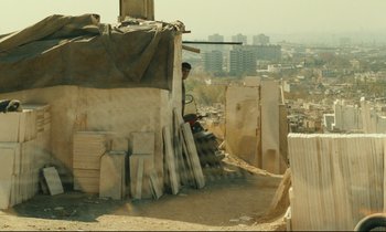 Movie still from “Taste of Cherry” (1997), directed by Abbas Kiarostami – A man standing next to a pile of wood; Wide shot, Over the shoulder angle