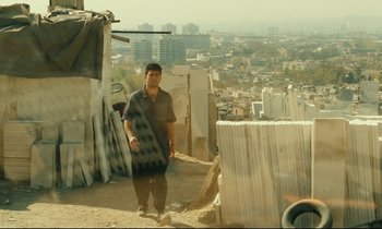 Movie still from “Taste of Cherry” (1997), directed by Abbas Kiarostami – A man standing on top of a building near a bunch of buildings; Wide shot, High angle