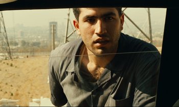 Movie still from “Taste of Cherry” (1997), directed by Abbas Kiarostami – A person looking out of a window; Close Up shot, Low angle