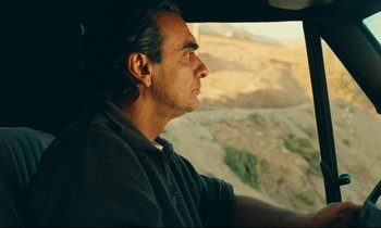 Movie still from “Taste of Cherry” (1997), directed by Abbas Kiarostami – A man sitting in the driver's seat of a car; Close Up shot, Over the shoulder angle