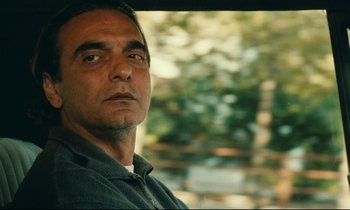 Movie still from “Taste of Cherry” (1997), directed by Abbas Kiarostami – A person looking at the camera; Close Up shot, Over the shoulder angle