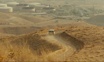 Movie still from “Taste of Cherry” (1997), directed by Abbas Kiarostami – A car driving down a dirt road in the middle of a desert; Extreme Wide shot, High angle