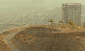 Movie still from “Taste of Cherry” (1997), directed by Abbas Kiarostami – An aerial view of a city and a hill with trees; Extreme Wide shot, High angle